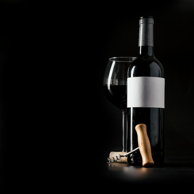 Zdjęcie korkociąg w pobliżu butelki i kieliszek wina