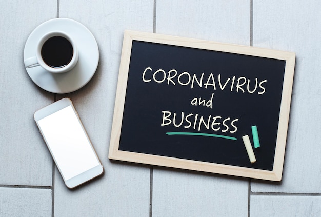 Koronawirus i tekst biznesowy napisany na tablicy COVID19 Wuhan Powieść Koronawirusowe zapalenie płuc Tablica kredowa z kawą i telefonem komórkowym