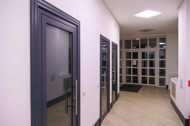Korytarz w miejskim biurowcu Nowoczesne wnętrze holu biurowca ze szklanymi drzwiami i czystymi białymi ścianami Oświetlony długi korytarz w nowoczesnym centrum biznesowym