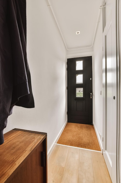 Zdjęcie korytarz z drewnianą podłogą i czarnymi drzwiami prowadzącymi do wejścia w mieszkaniu lub domu w kamienicy