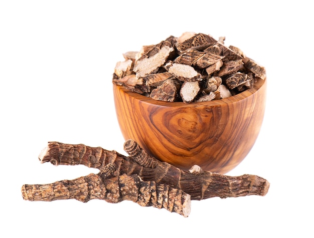 Zdjęcie korzeń tataraku w drewnianej misce izolowany na białym tle kołysze się słodka flaga lub korzeń piżmaka suchy korzeń