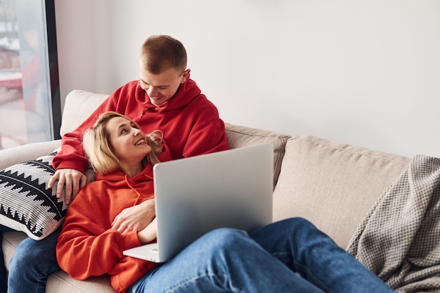 Korzystanie z laptopa na nogach Młoda urocza para razem w domu spędzająca razem weekend i wakacje