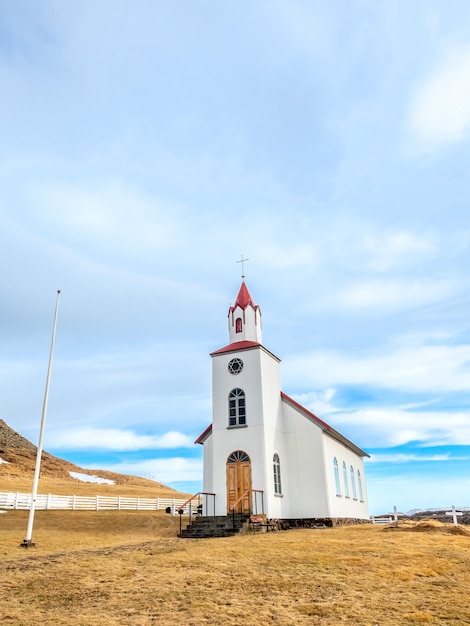 Kościół Helgafell klasyczna architektura budynek islandzkiego kościoła na wzgórzu w sezonie zimowym pod zachmurzonym błękitnym niebem