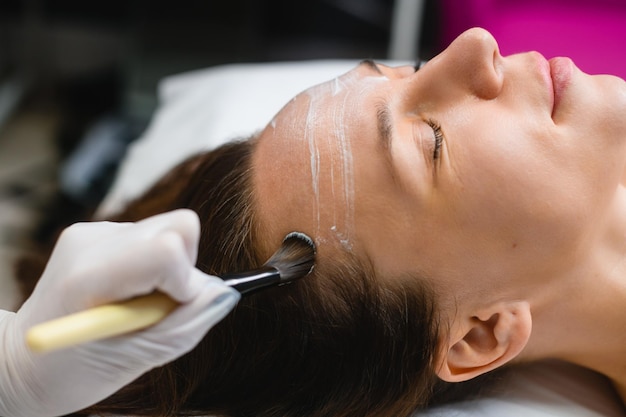 Zdjęcie kosmetolog nakłada maskę na twarz kobiety