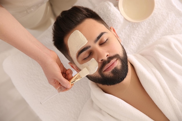 Kosmetolog nakłada maskę na twarz mężczyzny w widoku z góry salonu spa