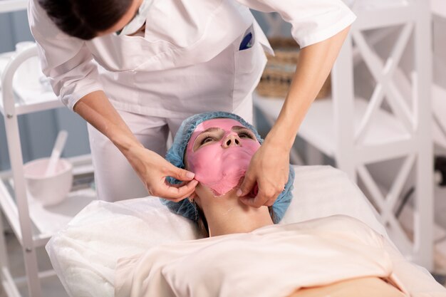 Kosmetolog Usuwa Różową Maskę Odnowy Biologicznej Z Twarzy Pacjenta