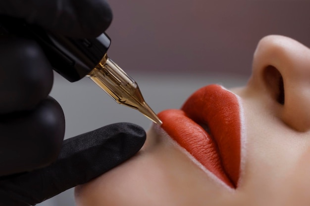 Kosmetolog wykonuje makijaż permanentny na twarzy kobiety Specjalista stosuje tatuaż na zbliżenie ust pacjenta