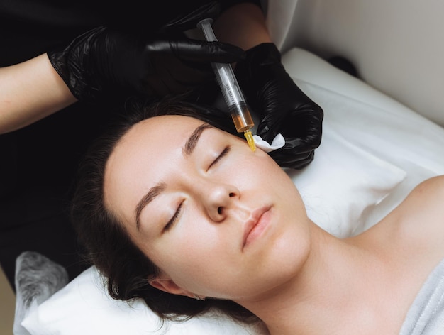 Kosmetolog wykonuje plazmolifting na twarzy pięknej kobiety w salonie kosmetycznym Koncepcja kosmetologii