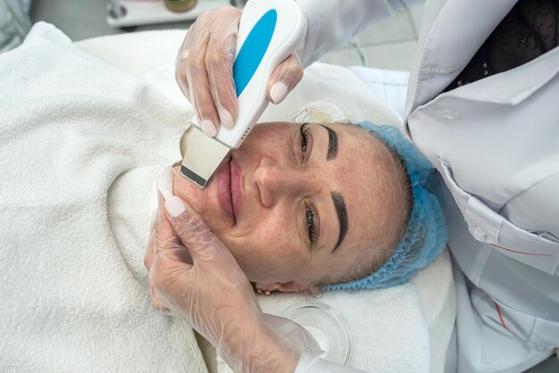 Zdjęcie kosmetolog wykonuje zabieg kawitacji na twarzy klienta w salonie
