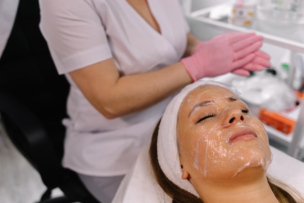 Kosmetyczka nakładająca maskę hydrożelową na twarz Klient kliniki kosmetologicznej