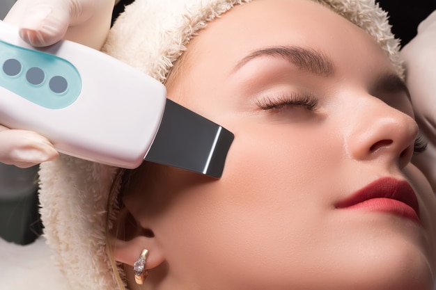 Zdjęcie kosmetyczka wykonuje ultradźwiękowe czyszczenie twarzy. kosmetologia sprzętowa.