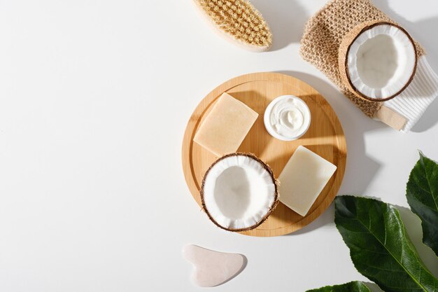 Kosmetyk ekologiczny na białym tle, naturalne ręcznie robione mydło, szczoteczka do ciała, płyn do mycia ciała, krem z kokosem, zielony liść, miejsce na kopię
