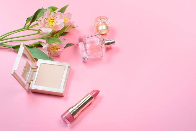 Kosmetyki i kwiaty na różowym stole z copyspace