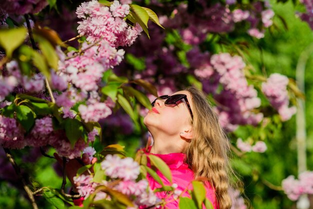 Kosmetyki naturalne do skóry. Dziewczyna w kwiat wiśni. Kwitnące drzewo Sakura. Małe dziecko dziewczynka w rozkwicie kwiat wiosny. Ciesz się zapachem delikatnego kwiatu. Koncepcja kwiat sakura. Wspaniały kwiat i kobiece piękno.