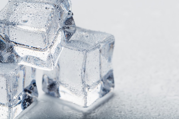 Kostki lodu w formie piramidy z kropli wody z bliska w makro na białym tle.