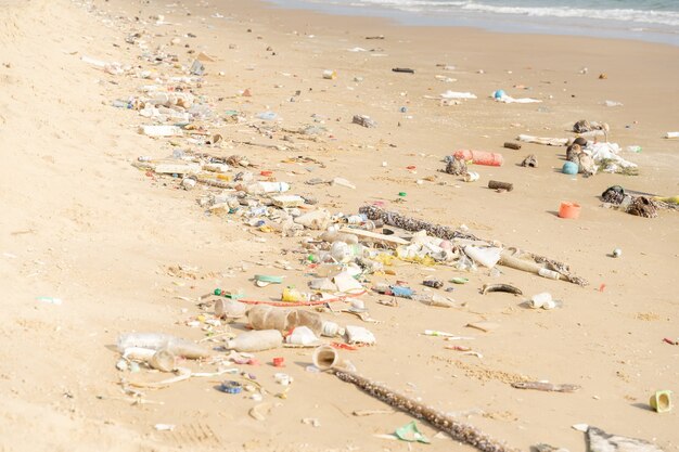 Kosz na tropikalnej plaży. Problem środowiskowy zanieczyszczenia tworzywami sztucznymi. Plastikowe butelki i inne śmieci wyrzucone na plażę.