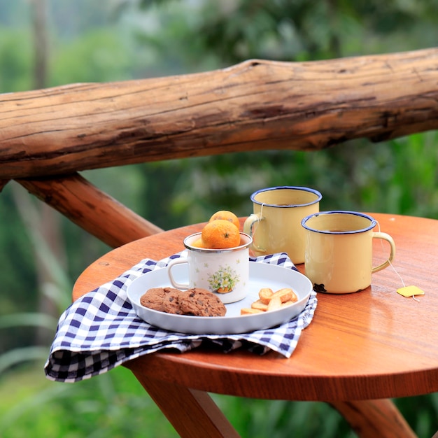 Kosz piknikowy z owocami i pieczywem na starym rustykalnym drewnianym stole z zieloną scenerią