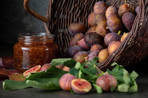 Kosz świeżych fig i słoik dżemu figowego na ciemnoszarym tle