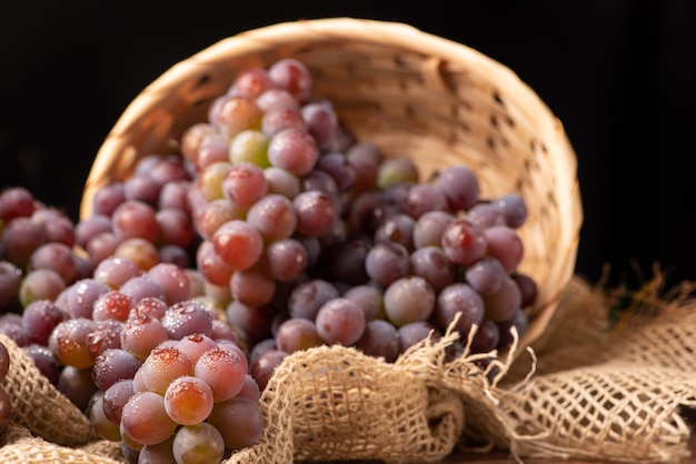 Kosz winogronowy z pięknymi winogronami i rustykalną tkaniną na rustykalnym drewnie selektywnym