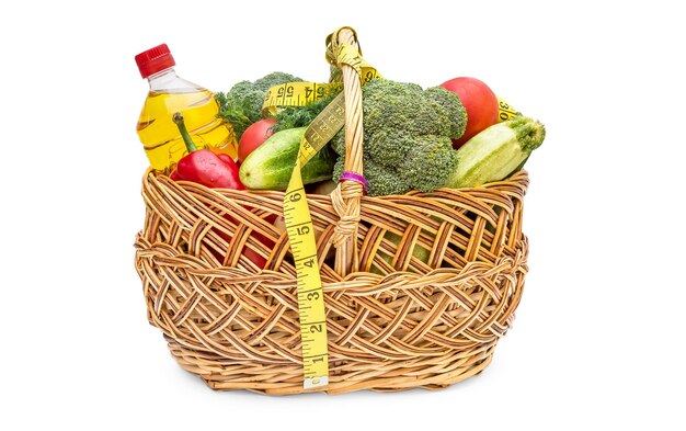 Kosz z warzywami, olejem do gotowania i taśmą mierniczą na białym koncepcie zdrowego odżywiania i diety