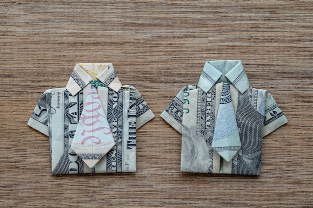 Koszula origami wykonana z banknotu dolara na podłoże drewniane. Ścieśniać. Koszulka z banknotem dolara
