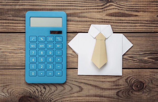 Koszula origami z krawatem i kalkulatorem na drewnianym stole Koncepcja biznesowa