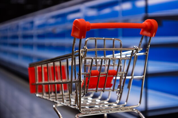 Koszyk na zakupy w supermarkecie z pustymi półkami Koncepcja niedoboru