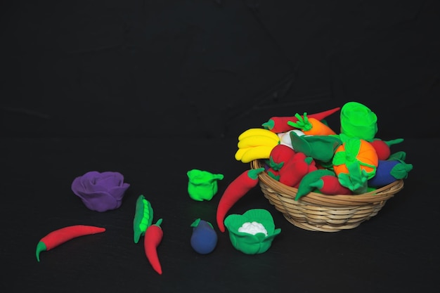 Koszyk warzyw i owoców z plasteliny na czarnym tle Koncepcja dostawy świeżej i zdrowej żywności Selektywne skupienie