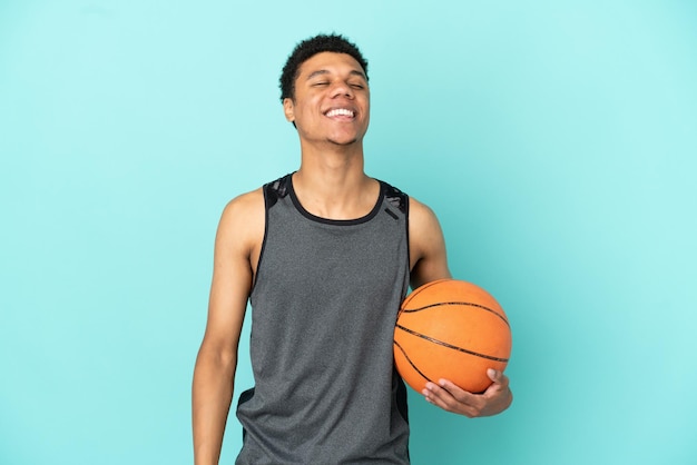 Koszykarz Afroamerykanin na białym tle śmiejąc się na niebieskim tle