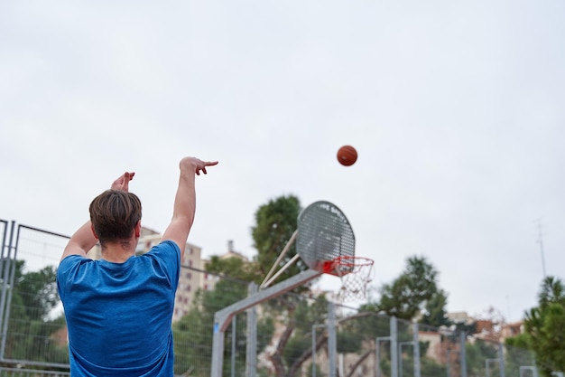 Koszykarz rzucający piłkę do kosza na boisku do koszykówki ulicznej