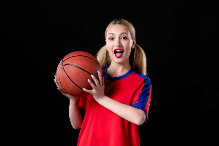 Zdjęcie koszykarz w sportowych ubraniach z piłką na czarnym tle gra ćwiczeń sportowców