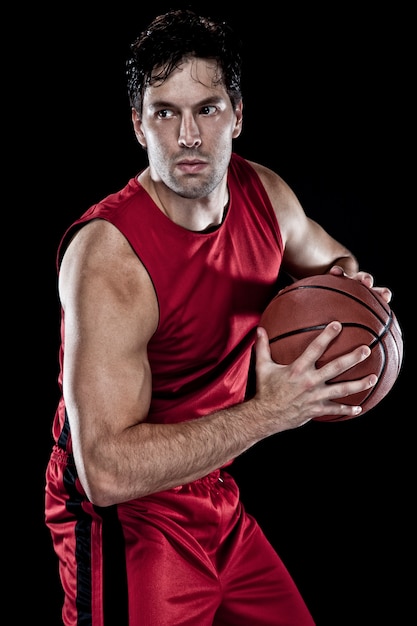 Koszykarz z piłką w dłoniach i czerwonym mundurze.