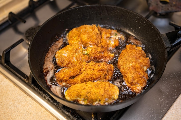 Kotlety z kurczaka na patelni w stylu rustykalnym selektywnym skupiają się na procesie gotowania na patelni smażonej