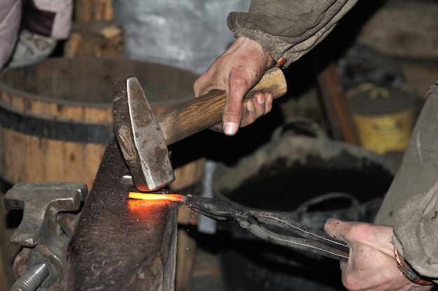 Kowal obróbka metalu młotkiem na kowadle w kuźni