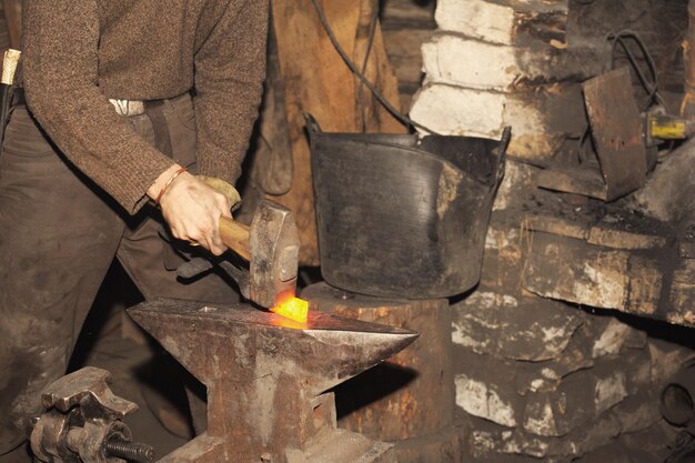 Kowal pracujący w kuźni obrabia metal Zdjęcie na temat kowalstwa