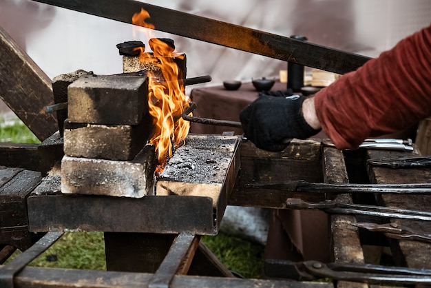 Kowal rozgrzewa metalowy produkt w ogniu kuźni