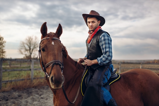 Kowboj w dżinsach i skórzanej kurtce na koniu na farmie teksasów, western. Vintage mężczyzna na koniu, kultura amerykańska