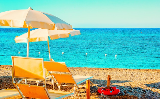 Krajobraz Chia Beach z parasolami i błękitnymi wodami Morza Śródziemnego w prowincji Cagliari na południu Sardynii we Włoszech. Krajobrazy i przyroda. Różne środki przekazu.