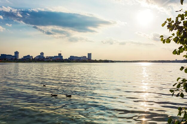 Krajobraz Jezioro i miasto na brzegu w promieniach zachodzącego słońca