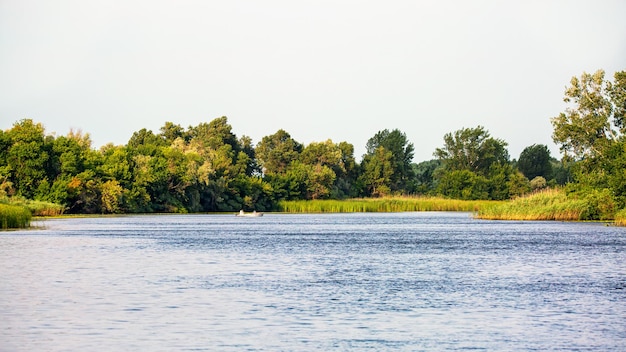 Krajobraz nad rzeką z rybakiem na łódce