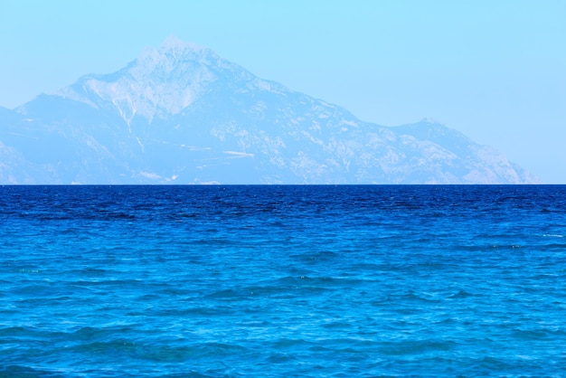 Krajobraz wybrzeża Morza Egejskiego z wodą seledynową i Mount Athos we mgle (widok z Chalkidiki, Grecja).