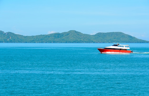 Krajobraz z czerwoną łodzią i morzem pod niebieskim niebem w ranku