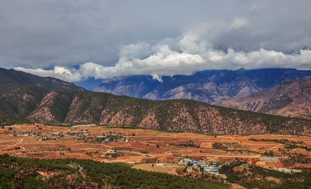 Krajobraz z górską żółtą rzeką i małą wioską u podnóża gór w Chinach