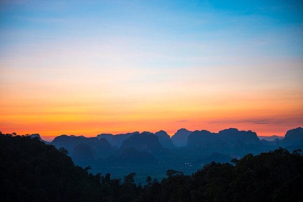 Krajobraz z pięknym dramatycznym zachodem słońca i sylwetką błękitnych gór na horyzoncie, Tajlandia