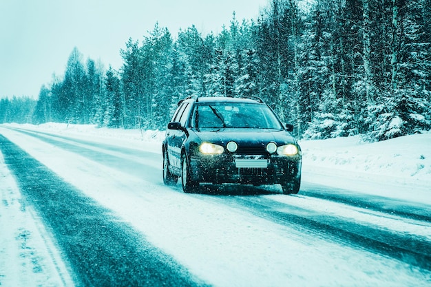 Krajobraz z samochodem w śnieżnej drodze w Finlandii. Wakacyjna podróż autostradą z naturą. Sceneria z zimową jazdą na wakacyjną podróż do rekreacji. Jazda ruchowa w Europie. Transport na podjeździe.