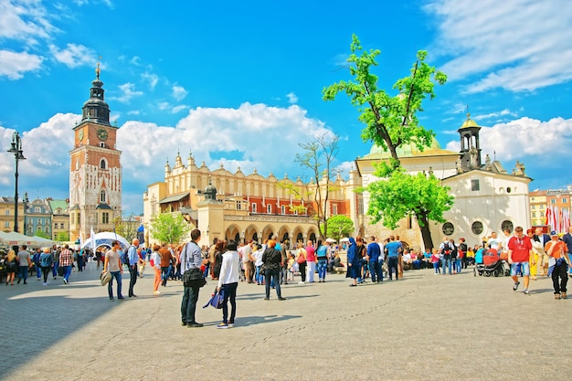 Kraków, Polska - 1 maja 2014: Ludzie w Sukiennicach i Wieży Ratuszowej na Rynku Głównym, Kraków, Polska