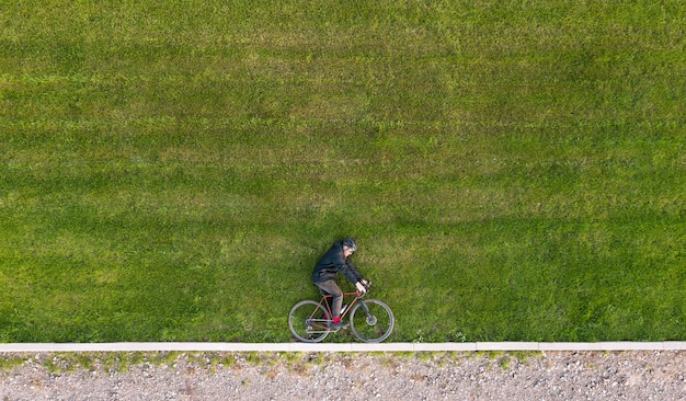 Kreatywna jesienna kompozycja rowerzysty leżącego na zielonym trawniku z rowerem. Minimalna koncepcja.