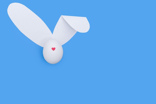 Kreatywna kartka okolicznościowa wykonana z białego jajka z czerwonym sercem zamiast nosa i białymi papierowymi uszami jak króliczek
