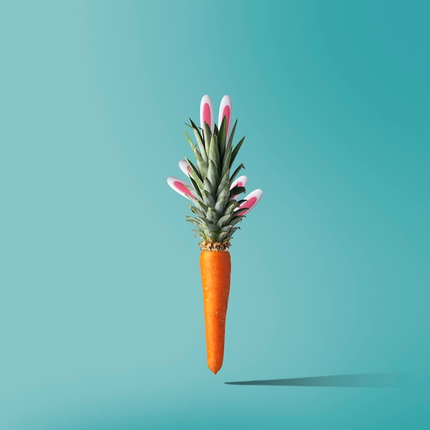 Kreatywna koncepcja Paschy Marchewki z liśćmi ananasa z wystającymi uszami królika
