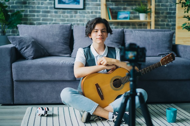 Kreatywna nastolatka nagrywająca wideo o rozmowie na instrumencie trzymającym gitarę